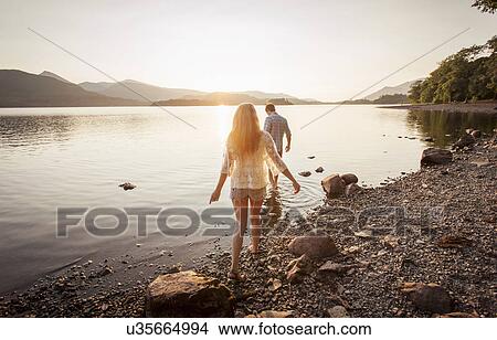 Picture - Young couple paddling in lake, Cumbria, England, UK. Fotosearch