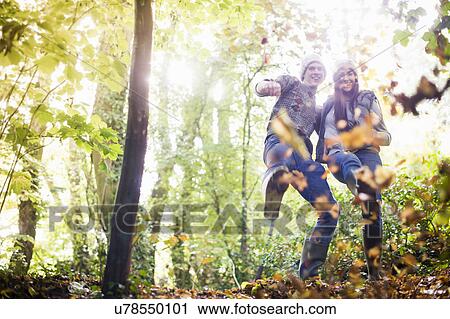 Stock Image - Young couple playing with autumn leaves in forest. Fotosearch
