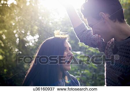 Stock Photo - Young couple playing with autumn leaves in forest. Fotosearch