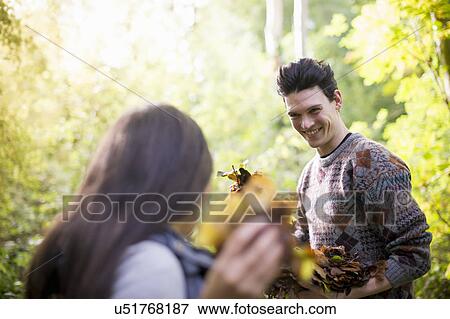 Stock Photo - Young couple playing with autumn leaves in forest. Fotosearch