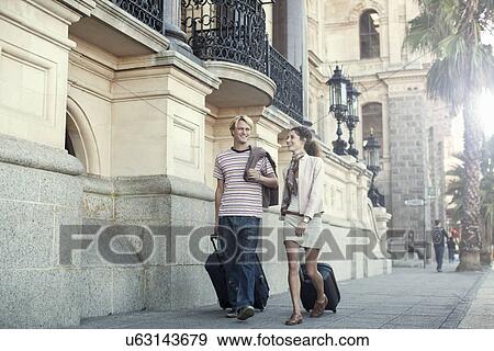Stock Photo - Young couple pulling suitcases, Cape Town, South Africa. Fotosearch