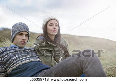 Stock Photo - Young couple sitting on beach, Brean Sands, Somerset, England. Fotosearch