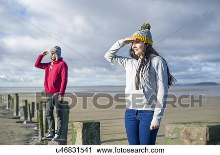 Stock Image - Young couple standing on groynes, Brean Sands, Somerset, England. Fotosearch