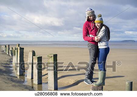 Young couple standing on groynes, Brean Sands, Somerset, England View Large Photo Image Stock Photo - Young couple standing on groynes, Brean Sands, Somerset, England. Fotosearch