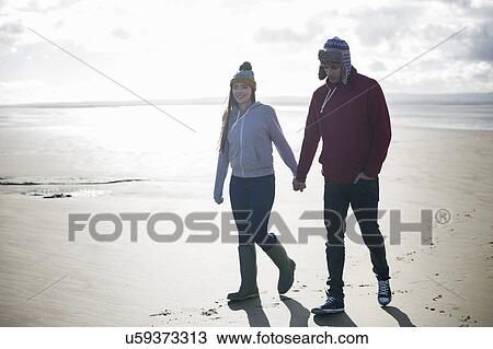 Stock Image - Young couple walking on beach, Brean Sands, Somerset, England. Fotosearch