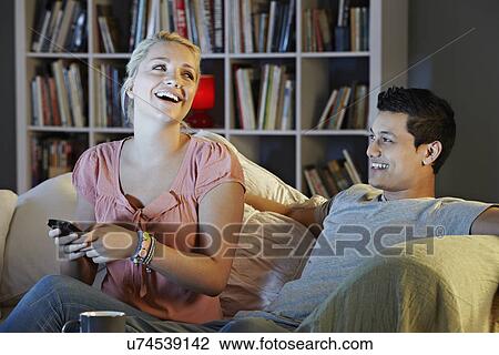 Young couple watching tv, laughing View Large Photo Image Stock Image - Young couple watching tv, laughing. Fotosearch