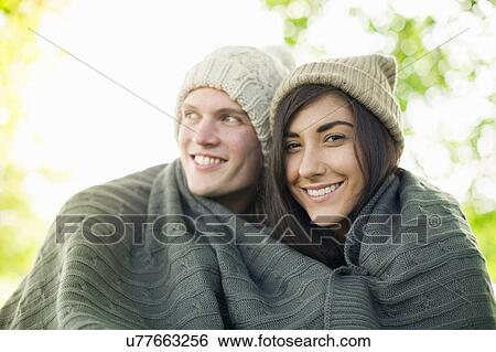 Young couple wearing knit hats wrapped in blanket View Large Photo Image Stock Photograph - Young couple wearing knit hats wrapped in blanket. Fotosearch