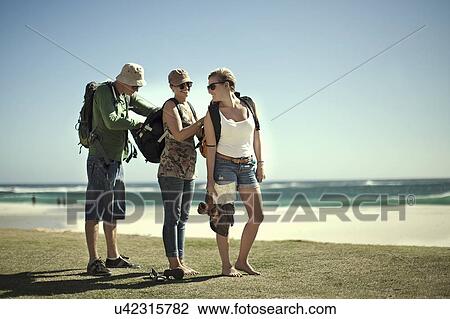 Stock Image - Young friends checking backpacks on beach, Cape Town, South Africa. Fotosearch