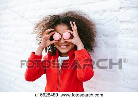 Young girl making face with macaroons View Large Photo Image Stock Photo - Young girl making face with macaroons. Fotosearch