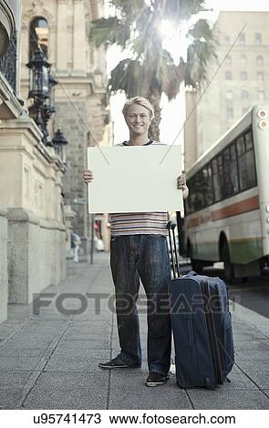 Stock Image - Young man holding blank white cardboard, Cape Town, South Africa. Fotosearch