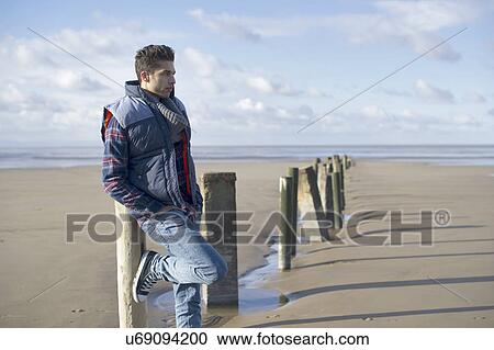 Young man leaning on groyne, Brean Sands, Somerset, England View Large Photo Image Stock Image - Young man leaning on groyne, Brean Sands, Somerset, England. Fotosearch