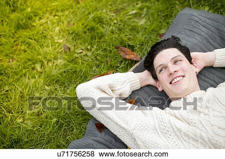 Stock Photo - Young man lying on rug wearing sweater. Fotosearch