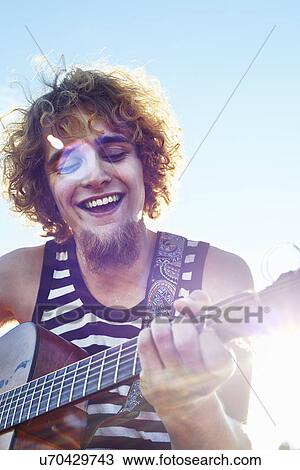 Young man playing guitar in sunshine View Large Photo Image Stock Image - Young man playing guitar in sunshine. Fotosearch