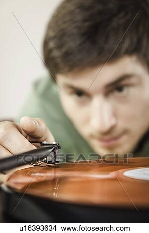 Picture - Young man playing vinyl record, close up. Fotosearch