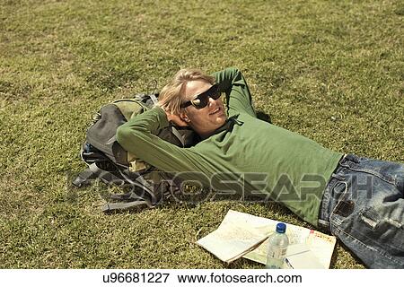 Stock Photo - Young man reclining in park with maps, Cape Town, South Africa. Fotosearch