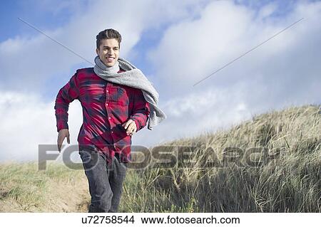 Picture - Young man running on sand dunes, Brean Sands, Somerset, England. Fotosearch