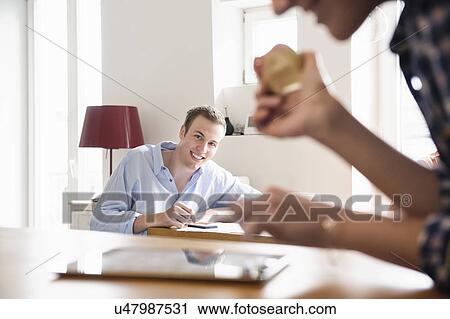 Young man seated smiling at a young woman eating an apple View Large Photo Image Stock Image - Young man seated smiling at a young woman eating an apple. Fotosearch
