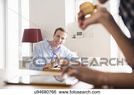 Young man seated smiling at a young woman eating an apple View Large Photo Image Stock Photograph - Young man seated smiling at a young woman eating an apple. Fotosearch