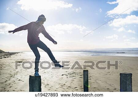Young man standing on groynes, Brean Sands, Somerset, England View Large Photo Image Stock Image - Young man standing on groynes, Brean Sands, Somerset, England. Fotosearch