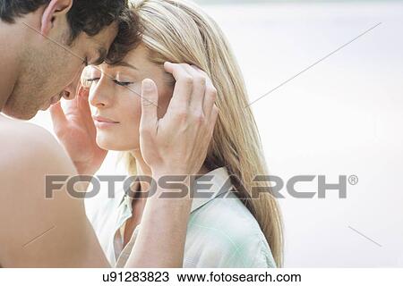 Stock Image - Young man touching woman's face. Fotosearch