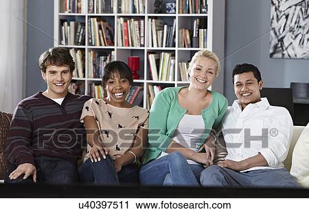 Young people sitting on sofa watching tv View Large Photo Image Stock Image - Young people sitting on sofa watching tv. Fotosearch