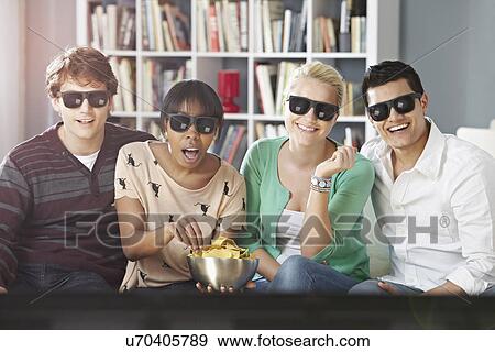 Young people watching 3D television, wearing 3D glasses View Large Photo Image Stock Photo - Young people watching 3D television, wearing 3D glasses. Fotosearch