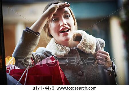 Young woman carrying shopping bag, looking through window View Large Photo Image Stock Image - Young woman carrying shopping bag, looking through window. Fotosearch