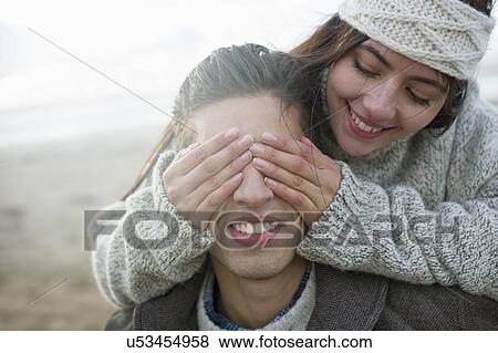 Stock Photo - Young woman covering mans eyes. Fotosearch