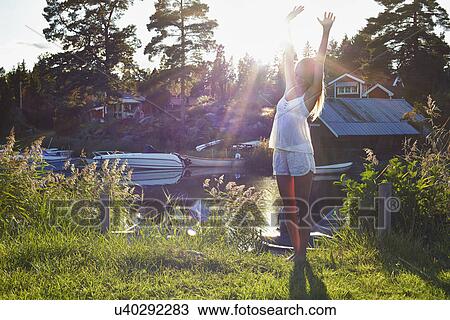 Stock Image - Young woman dancing next to lake, Gavle, Sweden. Fotosearch