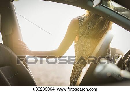 Picture - Young woman getting out of car. Fotosearch
