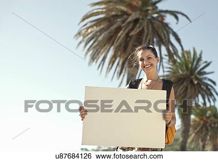 Stock Photograph - Young woman holding blank white cardboard, Cape Town, South Africa. Fotosearch