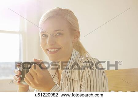 Stock Image - Young woman holding hot drink. Fotosearch