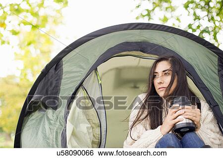 Stock Photograph - Young woman in tent holding flask. Fotosearch