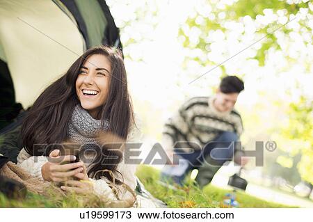 Young woman in tent using smartphone, laughing View Large Photo Image Stock Image - Young woman in tent using smartphone, laughing. Fotosearch