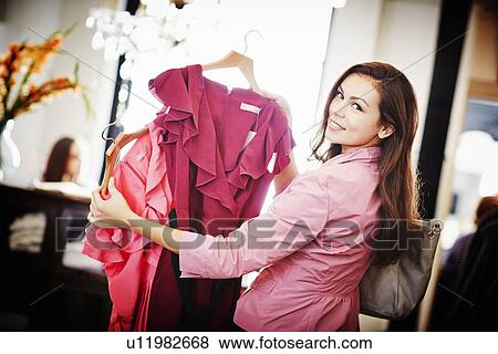 Young woman looking pink top on hanger View Large Photo Image Stock Photo - Young woman looking pink top on hanger. Fotosearch