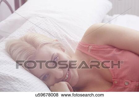 Young woman lying in bed View Large Photo Image Stock Photo - Young woman lying in bed. Fotosearch