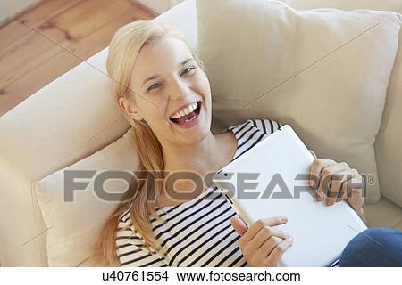 Young woman on sofa, using digital tablet View Large Photo Image Picture - Young woman on sofa, using digital tablet. Fotosearch
