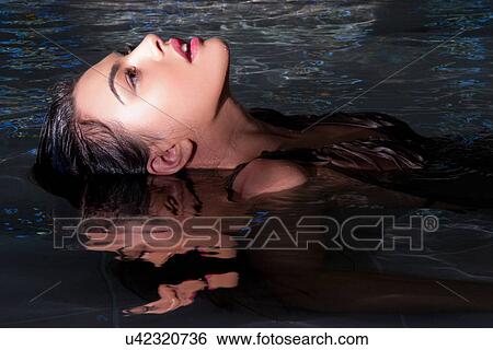 Stock Photograph - Young woman relaxing in spa swimming pool. Fotosearch
