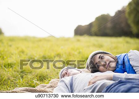 Stock Image - Young woman resting head on man's chest in park. Fotosearch