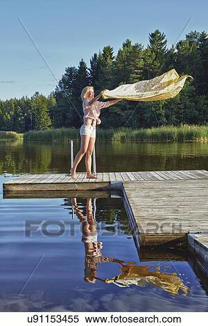 Young woman shaking blanket on pier, Gavle, Sweden View Large Photo Image Stock Photography - Young woman shaking blanket on pier, Gavle, Sweden. Fotosearch