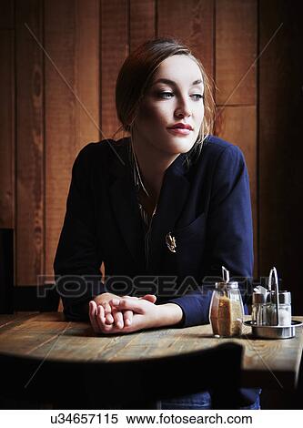 Young woman sitting in cafe with hands clasped View Large Photo Image Stock Photography - Young woman sitting in cafe with hands clasped. Fotosearch