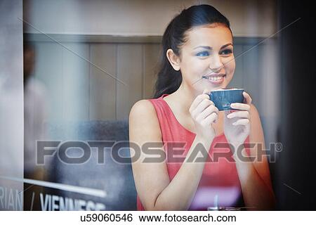 Young woman sitting in cafe with hot drink View Large Photo Image Stock Photograph - Young woman sitting in cafe with hot drink. Fotosearch