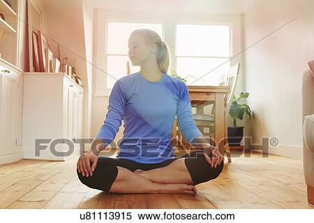 Stock Photography - Young woman sitting on floor cross legged. Fotosearch