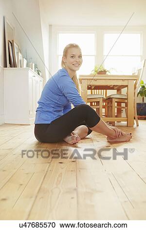 Young woman sitting on floor wearing sports clothing View Large Photo Image Stock Image - Young woman sitting on floor wearing sports clothing. Fotosearch