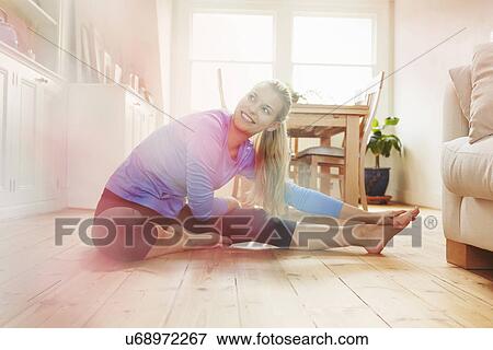 Young woman sitting on floor wearing sports clothing, stretching View Large Photo Image Stock Photo - Young woman sitting on floor wearing sports clothing, stretching. Fotosearch