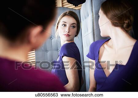 Stock Image - Young woman trying on dress, with friend. Fotosearch