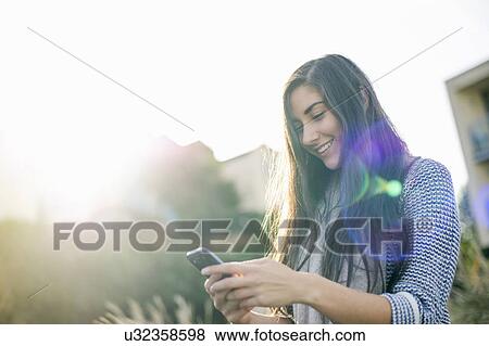 Stock Photo - Young woman using smartphone. Fotosearch