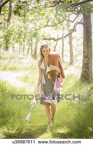 Stock Image - Young woman walking with bunting in forest. Fotosearch