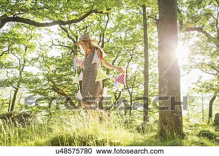 Stock Image - Young woman walking with bunting in forest. Fotosearch