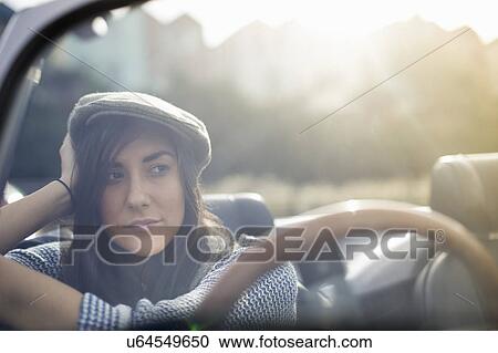 Young woman wearing flat cap in convertible View Large Photo Image Stock Image - Young woman wearing flat cap in convertible. Fotosearch